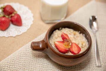 oatmeal porridge with strawberries and a glass of milk