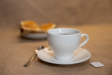 a white Cup of tea and a plate of sandwiches on the table