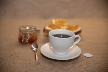 a white Cup of tea and a plate of sandwiches on the table