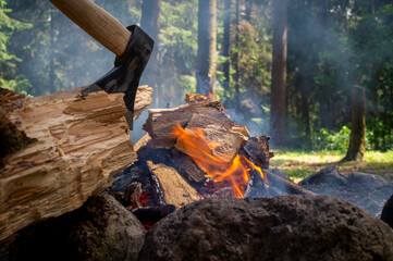 Camp fire in a forest with chopper in wood