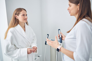 Confident ladies in white robe standing near the composition analyzed machine