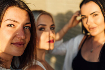 Photograph of three beautiful women smiling and looking into the camera on a sunny summer afternoon.