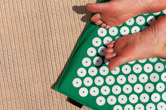 Female Feet Standing On Acupressure Mat. Self Acupuncture Massage.