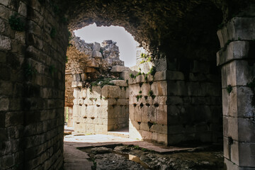 Ancient hallway in the ruins of a city with stone columns, floor meshed state and hole in the roof