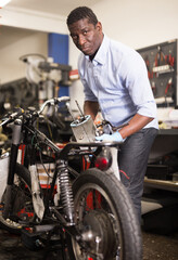 Fototapeta na wymiar Portrait of afro american man master who is repairing motobike. High quality photo