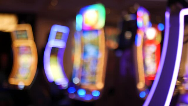 Defocused slot machines glow in casino on fabulous Las Vegas Strip, USA. Blurred gambling jackpot slots in hotel near Fremont street. Illuminated neon fruit machine for risk money playing and betting.