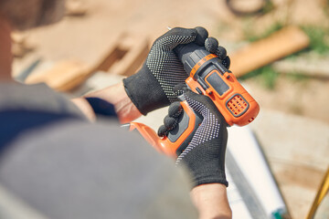 Builder in cut-resistant gloves preparing for driving screws