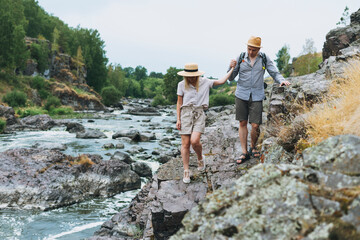 Young couple travelers in casual outfits hiking on mountain river. Local tourism, weekend trip