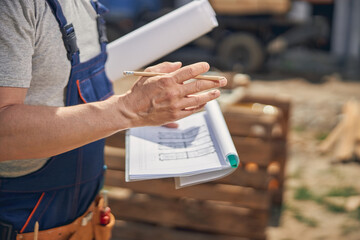 Man in work clothes holding house plans