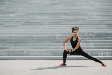 Fototapeta na wymiar Young woman and active workout on street. Girl in sportswear with fitness tracker does exercises on stairs
