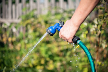 Gardener is watering a garden bed by a garden sprinkler close up.