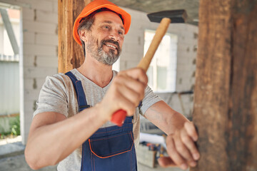 Cheerful carpenter looking at a timber beam
