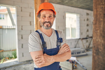 Joyful mature builder inside a half-finished house