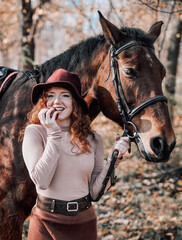 Fototapeta premium authentic portrait of beautiful redhaired woman with horse outdoors.