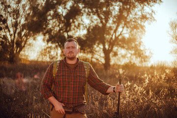 Irish looking red bearded hunter in checkered shirt staying outdoors in the sunset light and...