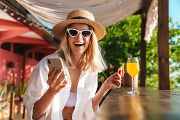 Image of joyful nice woman holding credit card and using cellphone