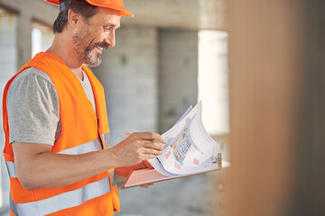 Man in a reflective waistcoat examining his blueprints