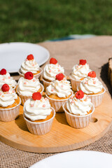 cupcakes with cream on a wooden tray outside