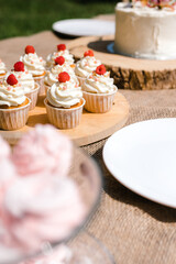 cupcakes with cream on a wooden tray outside