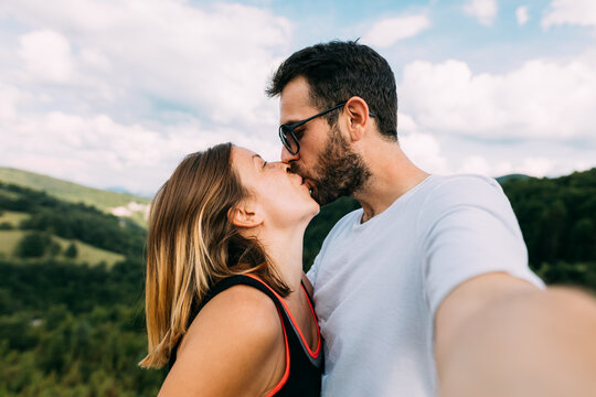 Young couple taking a selfie while kissing in the mountains