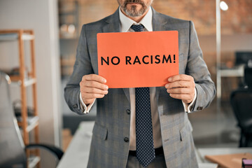 Man in suit holding no racism placard