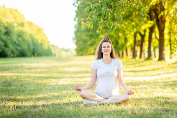 a pregnant girl does sports in nature in the summer, yoga for pregnant women in the fresh air