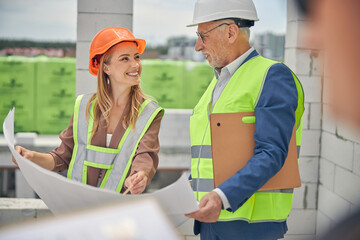 Cheerful lady in a helmet communicating with a foreman