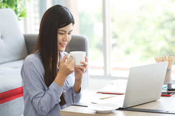 Happy casual beautiful woman working on a laptop sitting on the floor in the house.