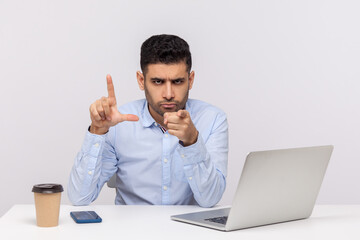You are fired! Strict man boss sitting office workplace, showing loser gesture and pointing finger to camera, reporting dismissal, accusing for failed project. studio shot isolated on white background