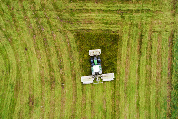 Fototapeta na wymiar An aerial of a tractor mowing a lush grassland in summer in rural Estonia, Northern Europe. 
