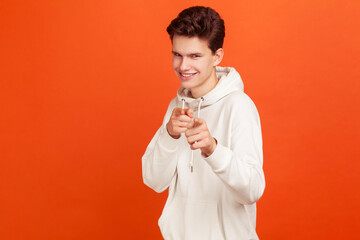 Young man with cunning smile pointing fingers on you smiling at camera. You are special. Victory in...