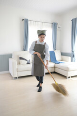 Young women cleaning house with broom