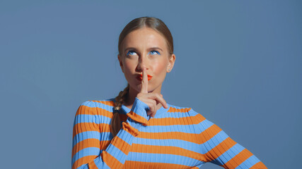 fun happy young girl with finger touches her lips with a sly face