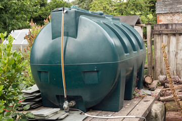 A green plastic fuel oil tank in a rural garden in Cornwall, England