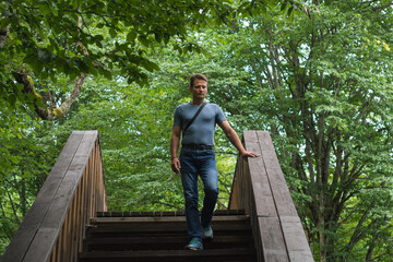 Man hiking through the forest, crossing a wooden bridge