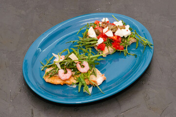 Bruschetta with shrimp, arugula, tomatoes, cheese and sauce on a gray background, top view. High Italian cuisine