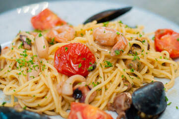 Spaghetti pasta with shrimp, mussels, tomatoes and cheese, close-up, side view. Tasty, traditional food Italians