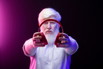 Fototapeta premium An albino man holding a pair of new, red headphones, isolated on a beautiful, colorful background.
