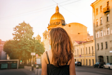 Back photo of a girl with long hair against the background of St. Isaac's Cathedral in St. Petersburg