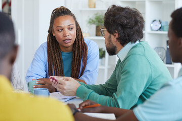 Portrait of contemporary African-American woman talking to colleagues during business meeting in office
