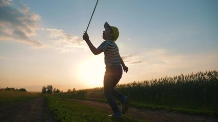 a happy child runs with a net on a sunset walk in the garden. Curious boy has fun outdoors, catching butterflies in the Park. Summer entertainment on a weekend.