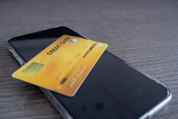 The yellow credit card is placed on a mobile phone, the concept of spending money via credit cards is simple and easy.