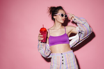 Image of confident woman in sunglasses drinking cocktail on camera