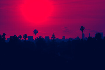 Fototapeta na wymiar Sunset over Los Angeles skyline with buildings and palm trees in California - red and blue duotone colors