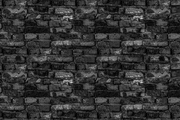 old shattered black stone wall part of the ruined house building in gloomy tones broken bricks