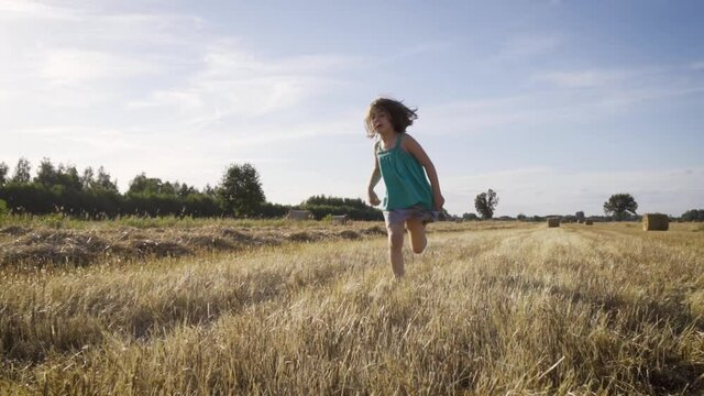 cute girl runs across the mown rye field