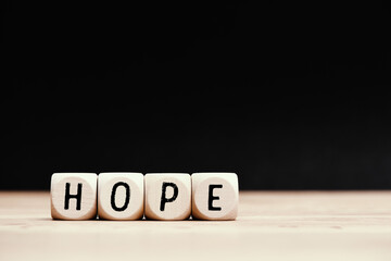 Social topic "Hope" written on wooden cubes with dark background