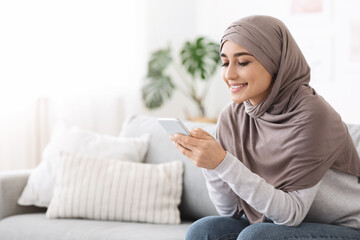 Online Banking. Smiling Muslim Woman Using App On Smartphone At Home