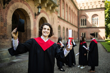 Smiling graduate smiling with her friends in background in front of the university