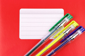 Red notebook and colorful gel pens. School education. Copy space. Place for text
